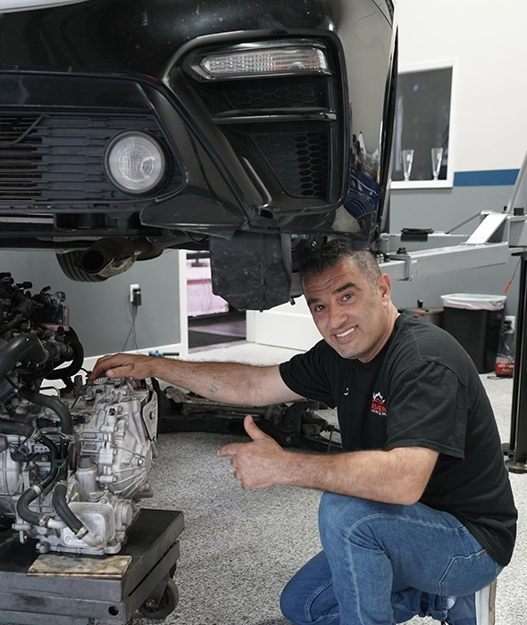 Mechanic Working Under Car Lift at Auto Repair and Smog Near Me Shop