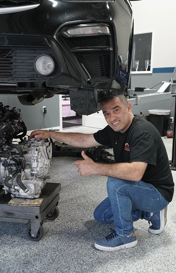 Mechanic Smiling While Inspecting Engine at Auto Repair Shop