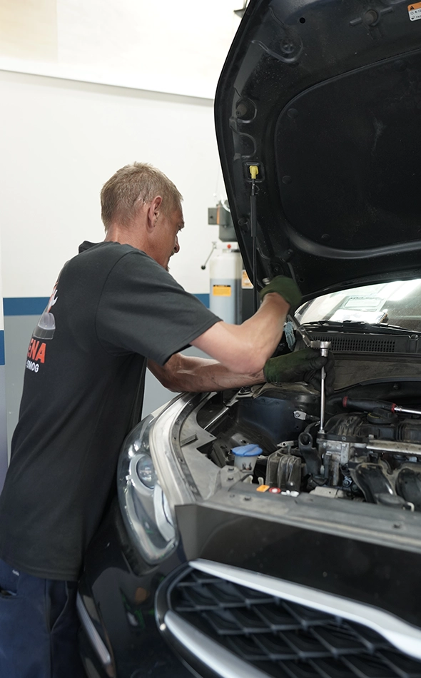 Mechanic Performing Auto Diagnostic Repair on Car in Garage Workshop